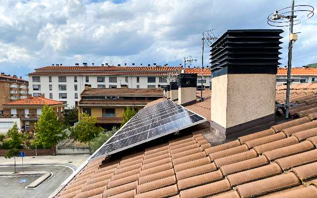 Paneles fotovoltaicos en tejado al lado de chimeneas